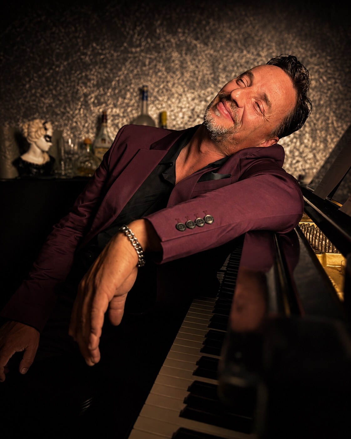Jack Rivers smiling and leaning against a piano